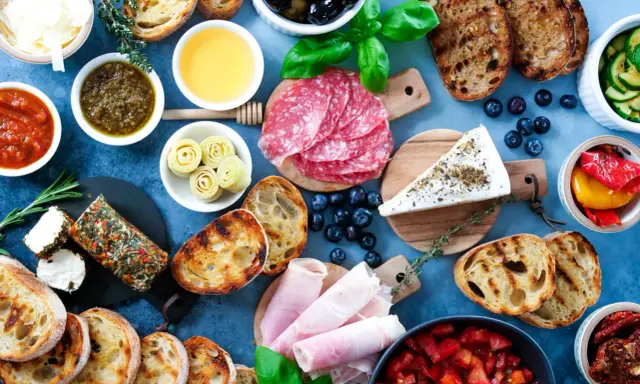 Eine köstliche italienische Vesperplatte mit Salami, Käse, Brot, Oliven und eingelegtem Gemüse.