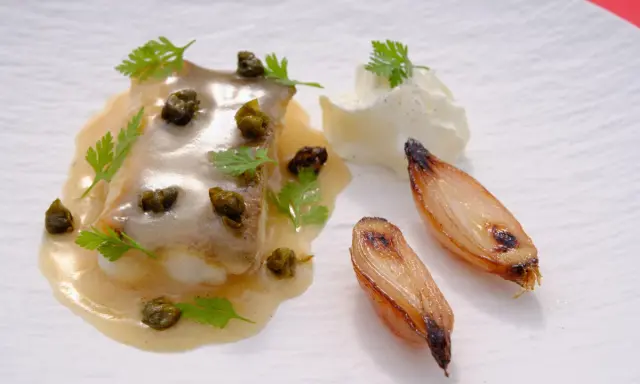 Delicioso lenguado a la meunière con alcaparras, perejil, cebollas caramelizadas y una quenelle de crema.