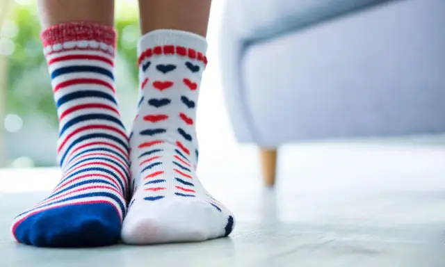 Zwei Paar bunte Socken, gestreift und mit Herzen, warten darauf, mit der richtigen Methode socken sauber bekommen zu werden.