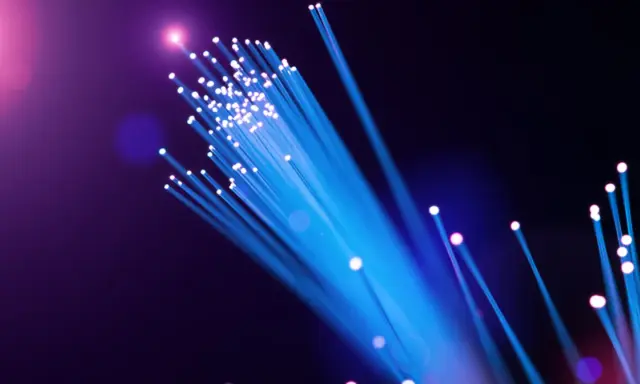 Leuchtende Glasfaserkabel in Blau und Lila. Die Frage "wie viel mbits sind gut wlan" wird durch die Darstellung von Highspeed-Datenübertragung visuell beantwortet.