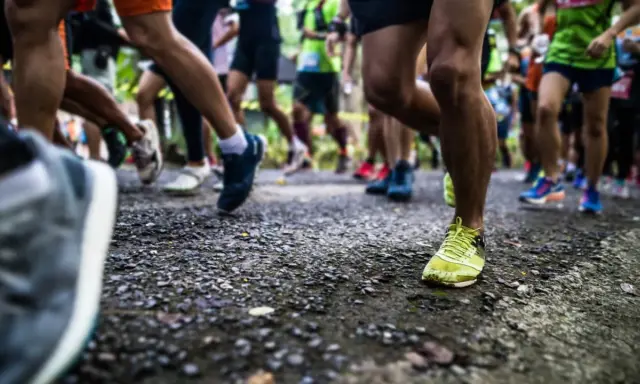 Läufer auf einer Strecke, die die halbmarathon distanz bewältigen. Fokus auf die Beine und Laufschuhe.