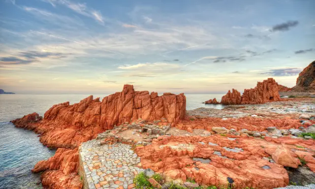 Scogliere rosse e sentiero in pietra a picco sul mare. Un luogo suggestivo da scoprire: Arbatax cosa vedere.