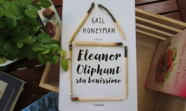 Copertina del libro "Eleanor Oliphant sta benissimo" di Gail Honeyman, con fiammiferi disposti a formare una casa.