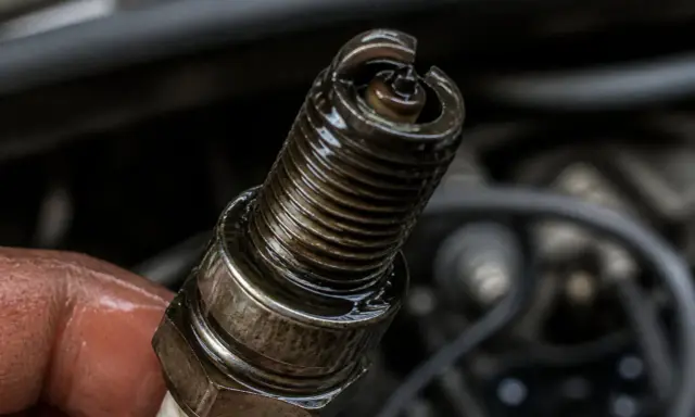 Bougie d'allumage d'un moteur 2 temps qui se noie, couverte d'huile.