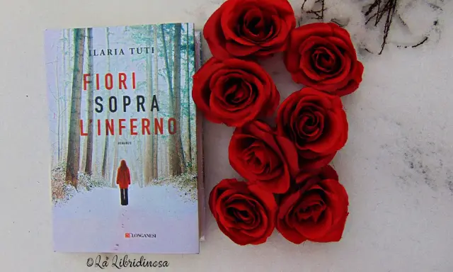 Copertina del libro "Fiori sopra l'inferno" di Ilaria Tuti, con rose rosse su sfondo innevato.