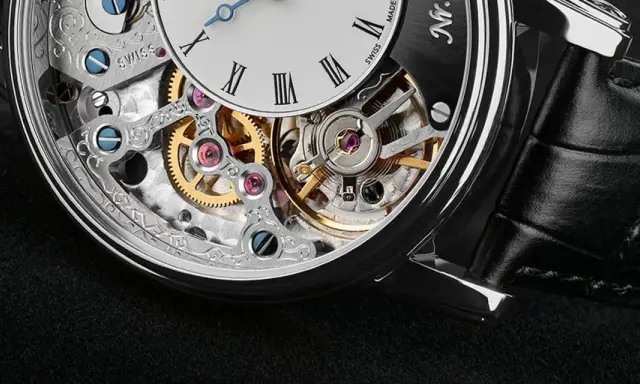 Dettaglio di un orologio scheletrato con ingranaggi dorati e rubini che riducono l'attrito, mostrando a cosa servono i rubini negli orologi.
