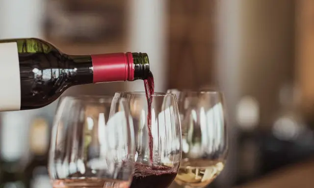 Rödvin hälls upp i glas under en vinprovning i Skåne. Rosé och vitt vin syns också.