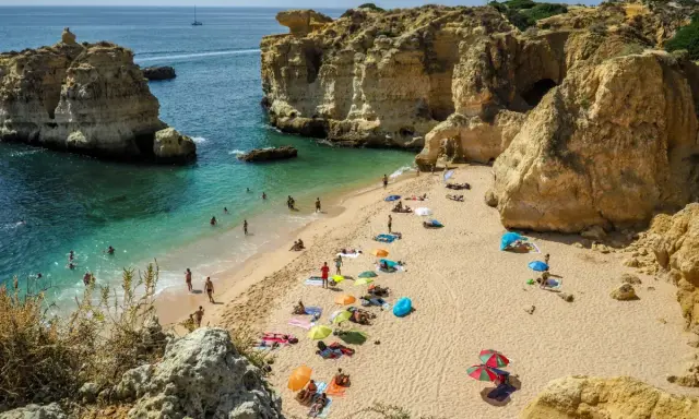 Słoneczna plaża w Algarve, z turkusową wodą i skalnymi klifami. Idealne miejsce, by zobaczyć piękno Portugalii.