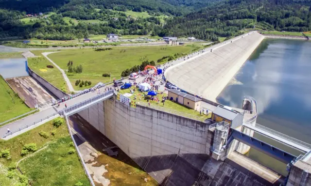 Impreza nad Jeziorem Mucharskim. Ludzie spacerują po zaporze, podziwiając widoki i korzystając z atrakcji.