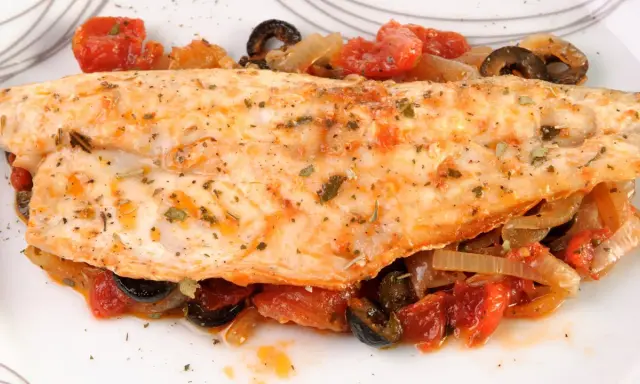 Leckerer Barsch zubereitet mit Tomaten, Zwiebeln und Oliven, garniert mit Kräutern. Ein Genuss für jeden Fischliebhaber.