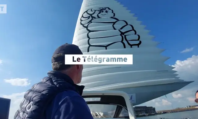 Un homme regarde une voile géante ornée du logo Michelin. Le Télégramme est affiché sur la voile.
