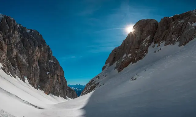 Sole che filtra tra le vette innevate, un invito a scoprire cosa vedere in Friuli Venezia Giulia, tra sentieri e panorami mozzafiato.