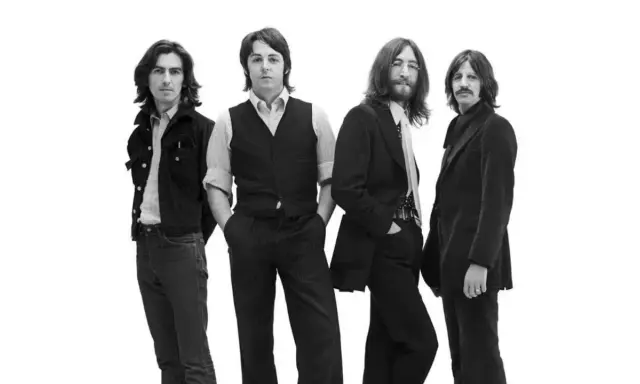 Les quatre membres des Beatles posent pour une photo en noir et blanc.