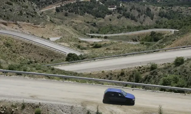 Coche azul en carretera de montaña con curvas pronunciadas. Podría recibir una multa por circular por pista forestal.