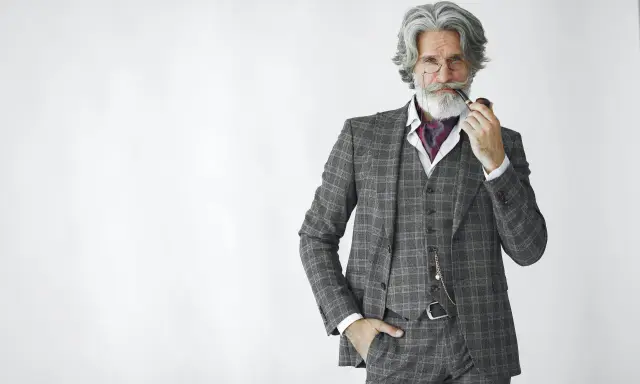 Distinguished gentleman in a plaid suit, vest, and ascot, holding a pipe. The perfect father of the groom attire.