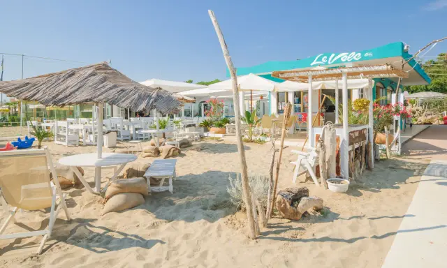 Un angolo di cervia strand con tavoli, sedie e ombrelloni di paglia, pronto ad accogliere i bagnanti.