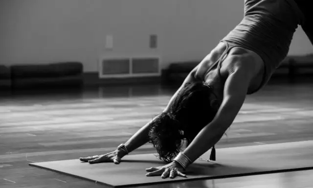 En person utför en nedåtgående hund-position under kundalini yoga.