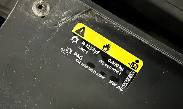 Naklejka informuje, jaki gaz do klimatyzacji samochodowej: R-1234yf, 0.460 kg. Zawiera też oznaczenie PAG.