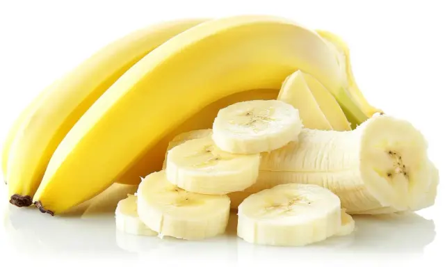 Kilka żółtych bananów, jeden obrany i pokrojony w plastry. Idealny banan na zatrucie pokarmowe.