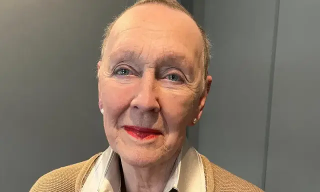Åldfrun Ebba von Mecklenburg, med sina blå ögon och röda läppar, bär en beige kofta och ett pärlhalsband.