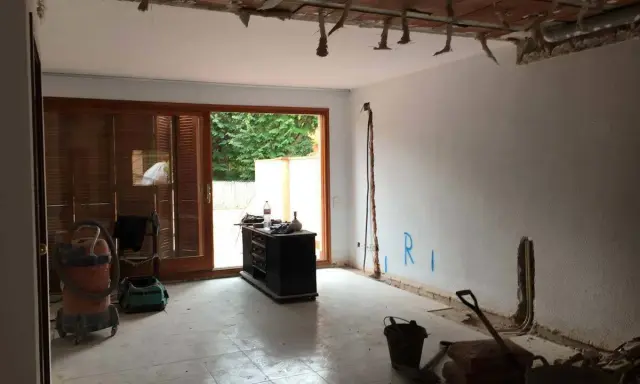 Interior de una casa de pueblo en plena reforma. Se ven materiales de construcción, herramientas y un aspirador.
