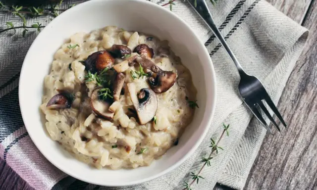 Risotto crémeux aux champignons, garni de thym frais. Une alternative savoureuse au vin blanc pour un risotto parfait.