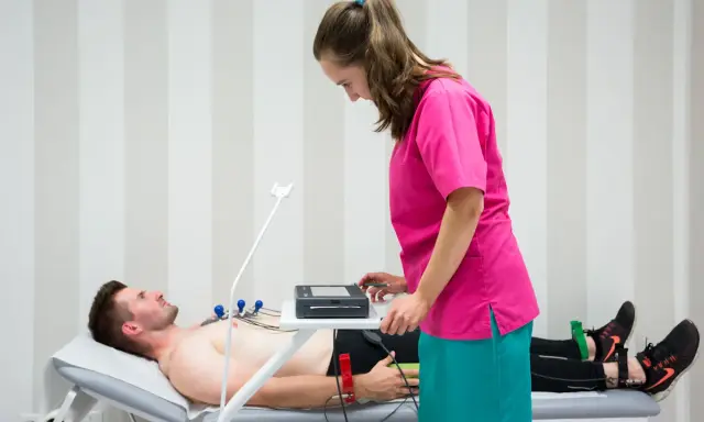 Mężczyzna leży na kozetce, pielęgniarka przygotowuje mu ekg spoczynkowe. Ile trwa badanie? Krótko, by ocenić pracę serca.