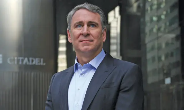 Ken Griffin, w eleganckim garniturze, stoi przed budynkiem z napisem "CITADEL".