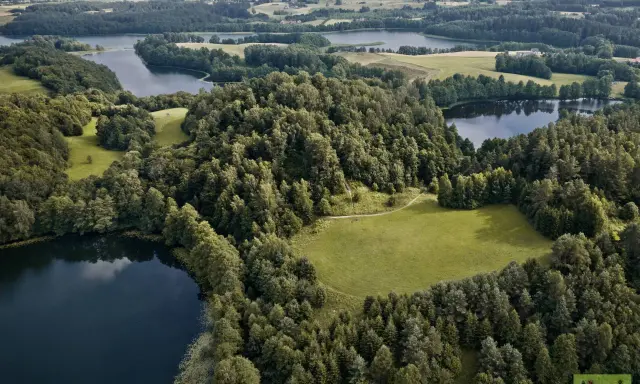 Krajobraz z jeziorami i lasami, typowy dla tego, z czego słynie Podlasie. Zielone pola i spokojne wody tworzą malowniczy widok.