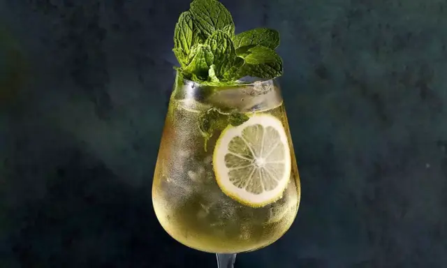Un verre de Hugo Spritz rafraîchissant, garni de menthe fraîche et d'une tranche de citron. Parfait pour une recette d'été.