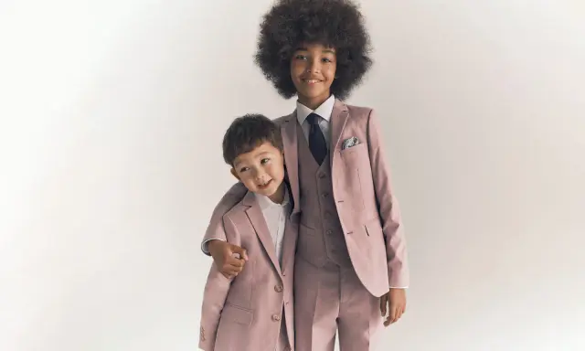 Two boys in matching dusty rose suits, showing what ring bearers wear: tailored jackets, vests, shirts, and ties.