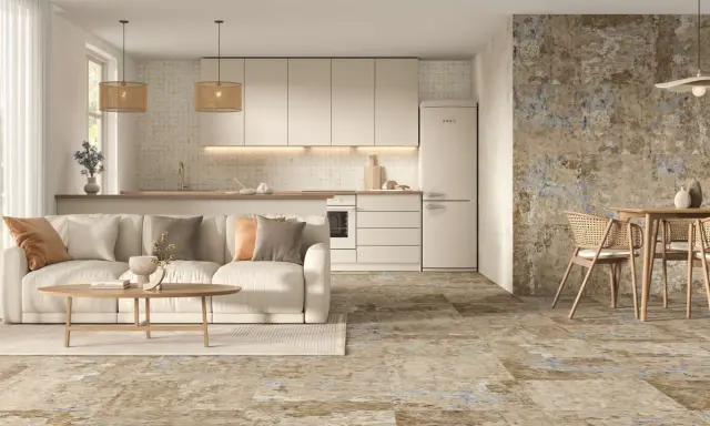 Elegante salón-cocina con sofá beige, mesa de centro de madera y suelos de cemento con un diseño rústico y texturizado.
