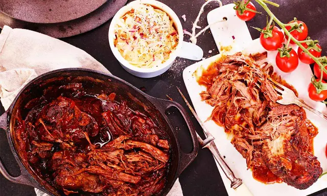 Saftigt pulled beef i en gjutjärnsgryta, serverat med krispig coleslaw och färska tomater. Perfekt för en mysig middag.