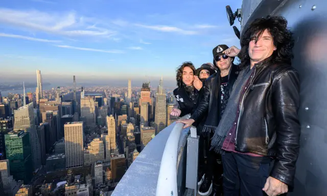 Les membres du groupe KISS posent sur un gratte-ciel new-yorkais, offrant une vue imprenable sur la ville.