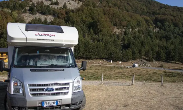 Camper parcheggiato in un'area panoramica della Calabria, con boschi e montagne sullo sfondo. Un'avventura in camper indimenticabile.