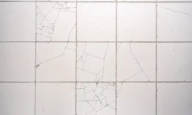 Uszkodzone płytki ceramiczne, widoczne pęknięcia tworzą mozaikę. Reklamacja płytek po położeniu jest konieczna.