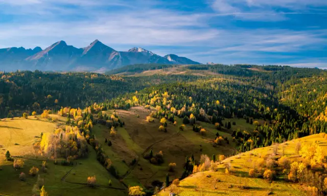 Jesienne Tatry Słowackie zachwycają kolorami. Widok na łagodne wzgórza i lasy, idealne na szlaki dla średnio zaawansowanych.
