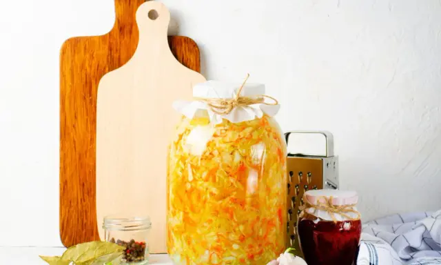 Großes Glas mit Sauerkraut, bereit zum **fermentieren im Schraubglas**. Daneben Gewürze, Knoblauch und ein kleines Glas Marmelade.
