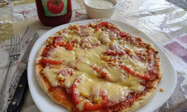 Pyszna pizza z patelni z serem, pomidorami i kukurydzą, obok ketchup i sos.