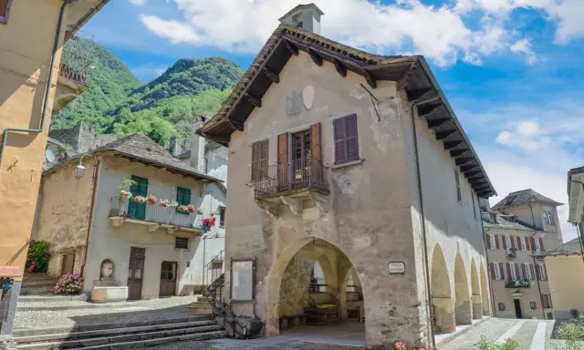 Un borgo antico con case in pietra e balconi fioriti, incastonato tra montagne verdi. Un luogo che fa venire vogogna cosa vedere, per la sua bellezza autentica.