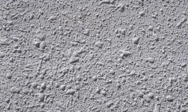 Textura gris de pared con relieve irregular, típica del **el gotelé**, que crea un efecto rugoso y con pequeñas protuberancias.