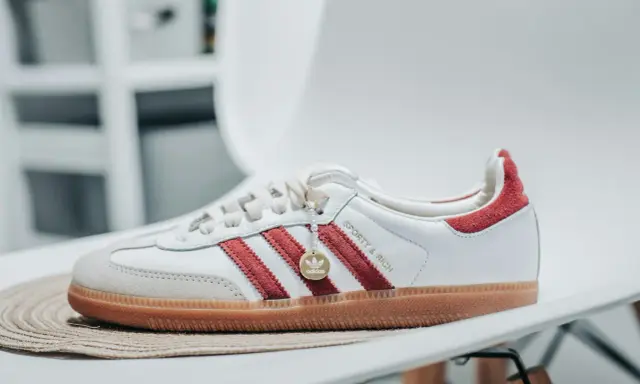 Białe buty adidas Samba z czerwonymi paskami i złotym logo. Sprawdź adidas samba rozmiarówka, by wybrać idealną parę.