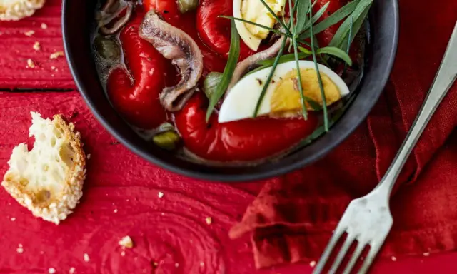 Salade de poivrons grillés avec anchois, câpres, œuf dur et herbes fraîches, servie avec du pain grillé.