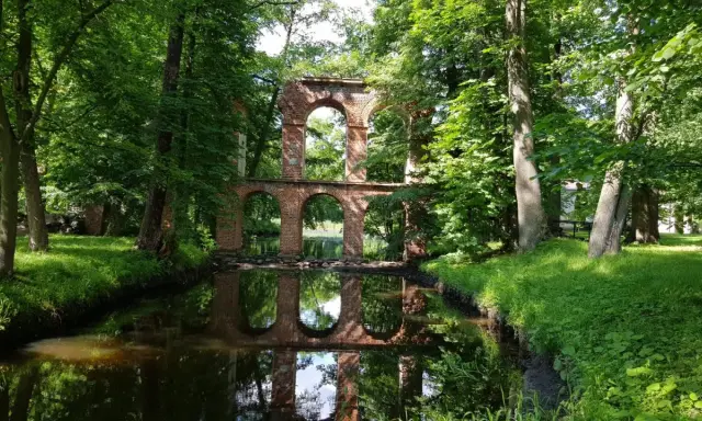 Ruiny mostu z cegły nad kanałem, otoczone zielenią. Idealne na weekendowe wycieczki, to jedne z fajnych miejsc niedaleko Warszawy.