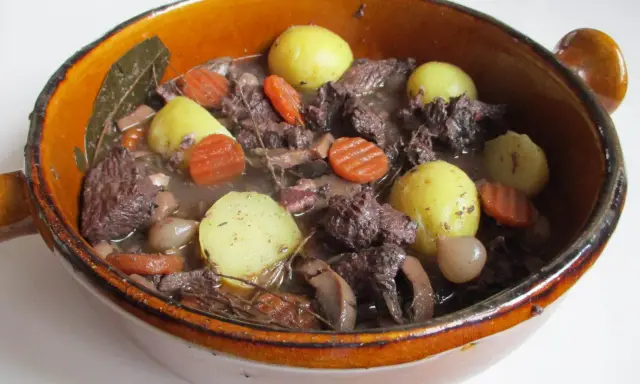 Un plat mijoté, spécialité culinaire Provence, avec du bœuf, des carottes, des pommes de terre et des oignons dans un jus savoureux.