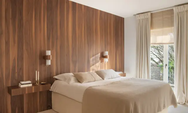 Dormitorio con cabecero de madera natural, creando un ambiente sereno y un cabecero feng shui. Cama confortable con mantas cálidas y luz tenue.