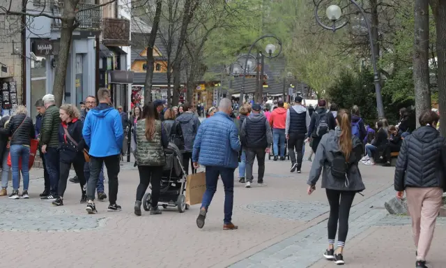 Spacer po Krupówkach, gdzie można spotkać znanych ludzi z Zakopanego. Tłum turystów i mieszkańców przemierza deptak.