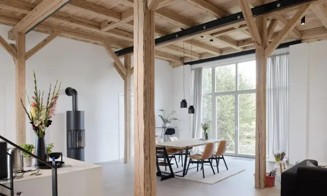 Moderne umgebaute Scheune mit Holzbalken und großem Fenster. Tolle Scheune umbauen Ideen für ein helles Wohnambiente.