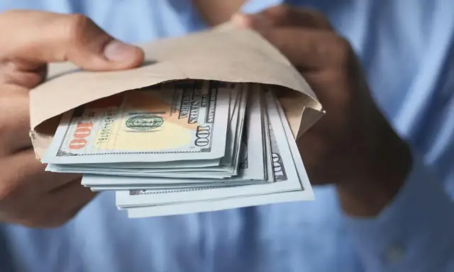 Zwrot podatku przekazem pocztowym a komornik – stos pieniędzy w kopercie.