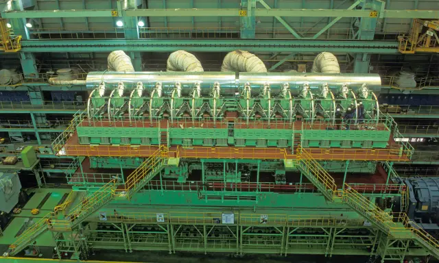 Vue aérienne d'un moteur de bateau massif, le plus gros moteur de bateau jamais construit, avec des ouvriers inspectant son imposante structure verte et argentée.